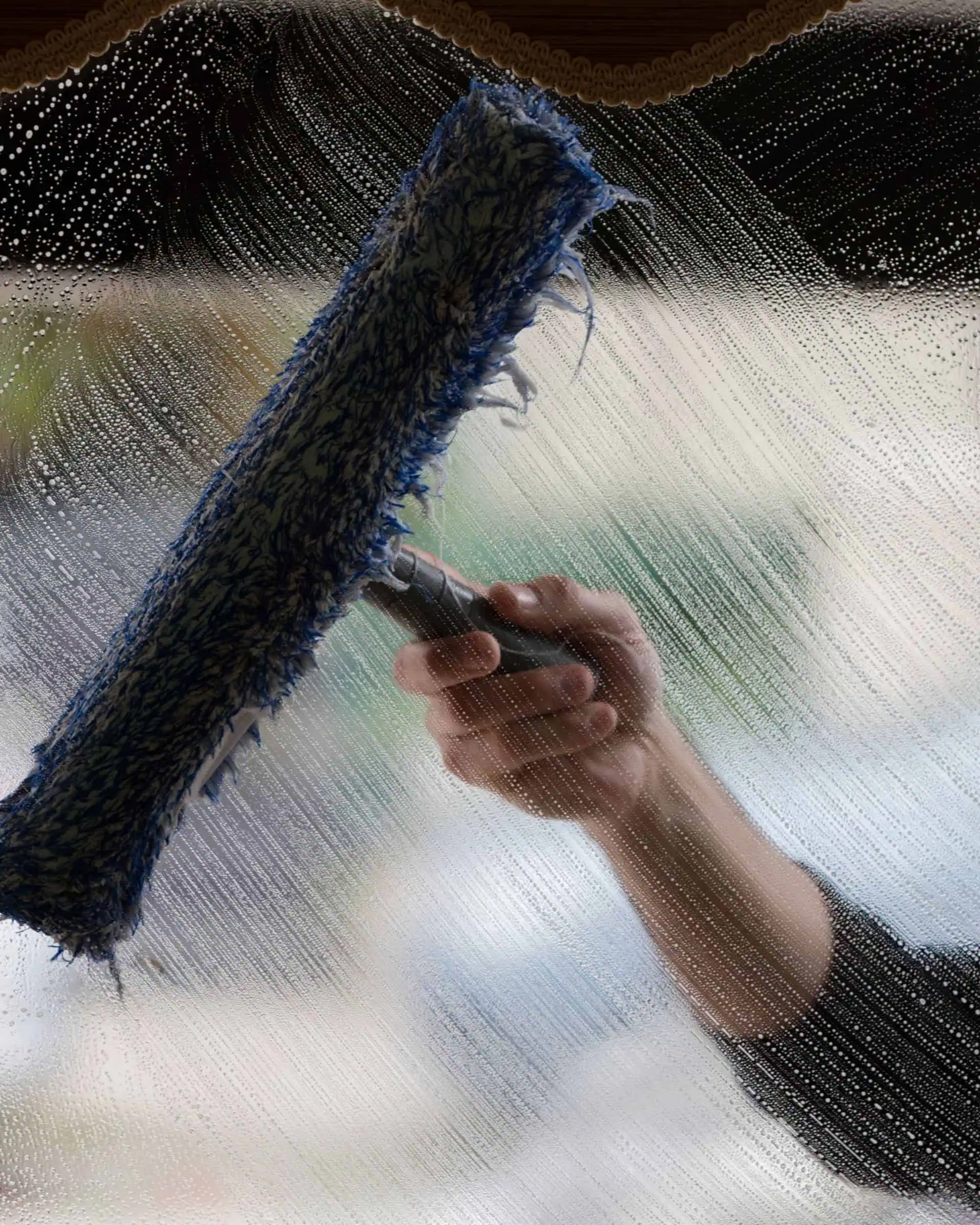 Primgaard technician cleaning interior window with squeegee – streak-free finish using purified water